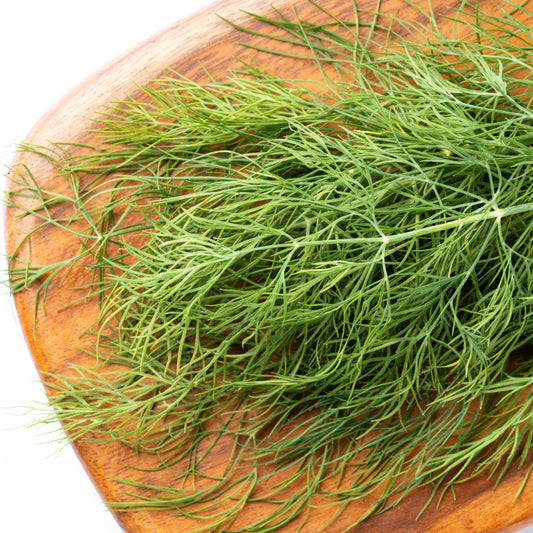 Fresh organic dill leaves on a wooden cutting board, perfect for culinary use