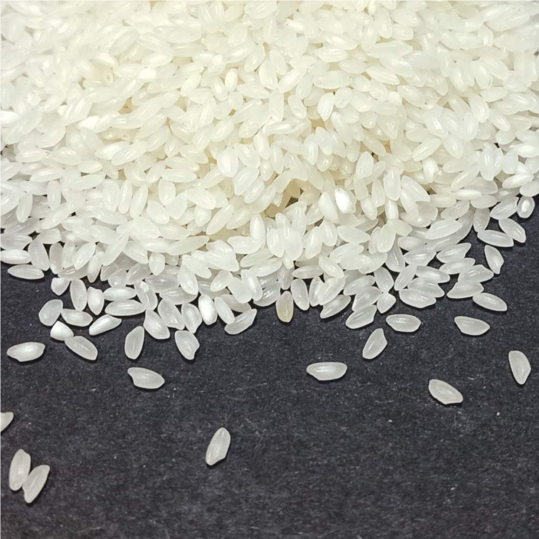 Premium quality organic ambemohar rice grains spread on a dark surface for cooking and meal preparation