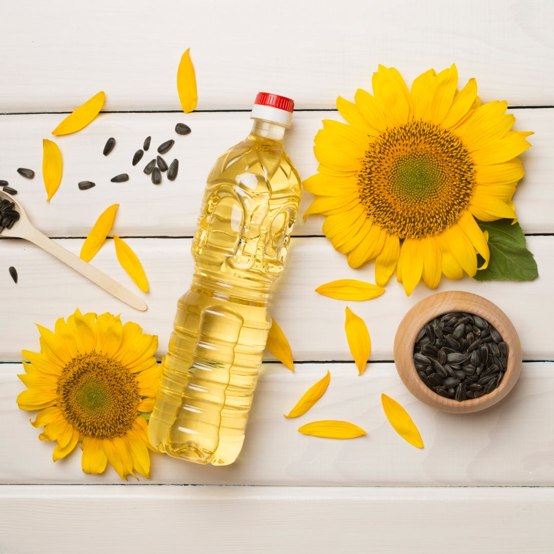 Organic cold pressed sunflower oil bottle with sunflower flowers and seeds on a wooden surface