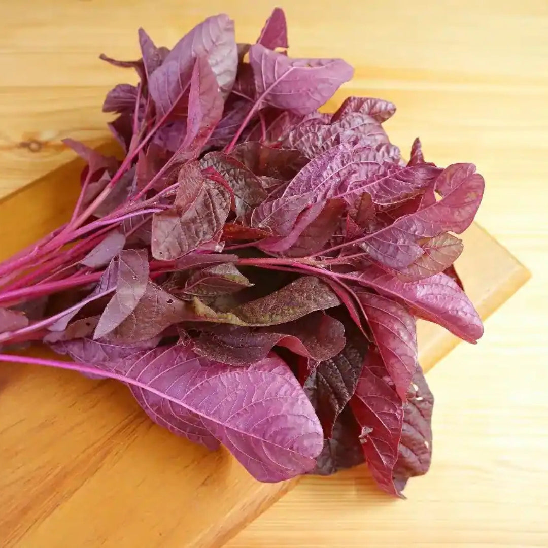 Fresh organic red amaranthus leaves arranged on a wooden cutting board