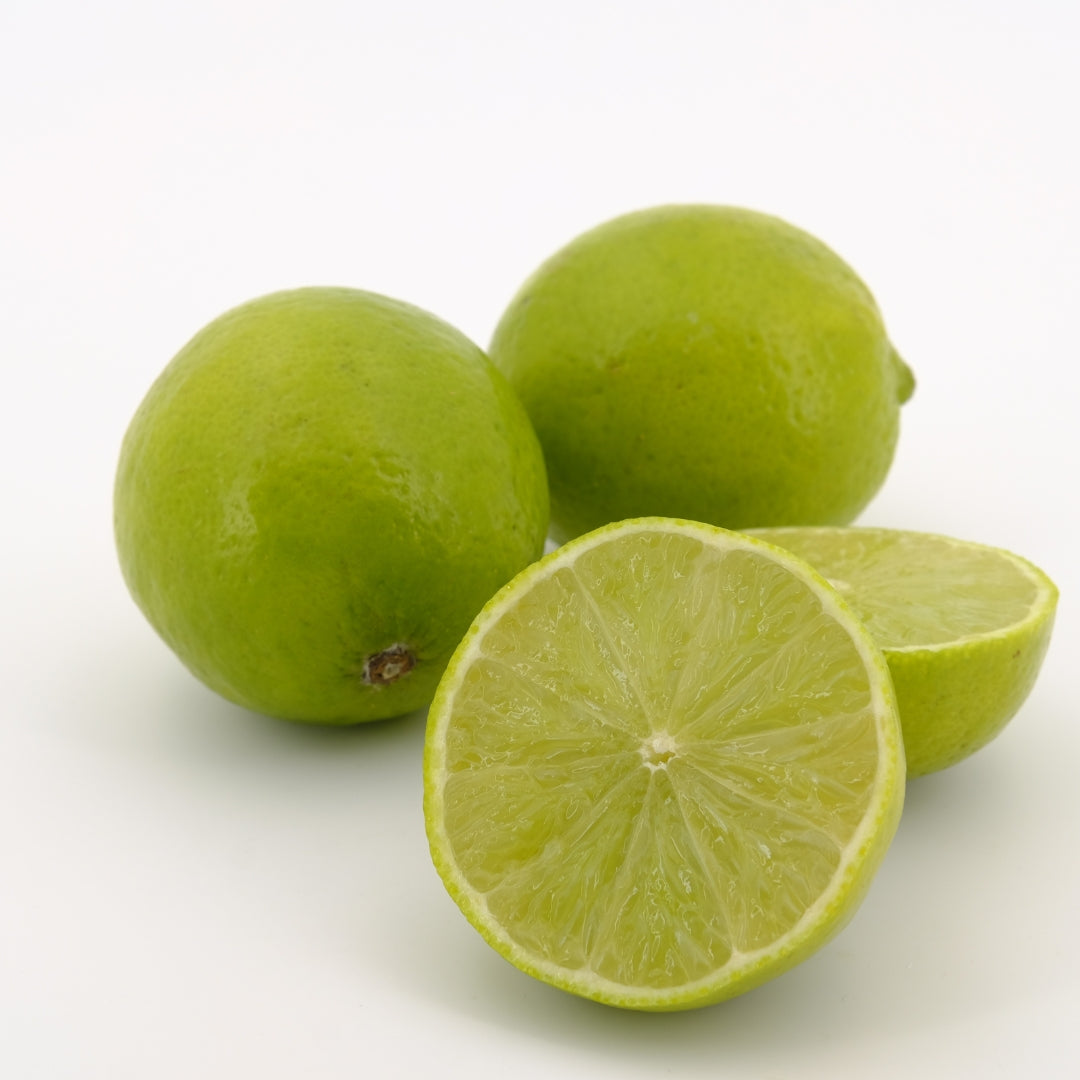 Three organic sweet limes, one cut in half to show juicy interior, on a white background