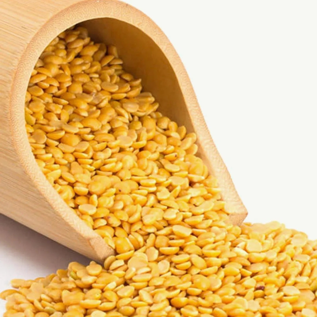 Organic tur dal spilling from a bamboo container, showcasing its vibrant yellow color and texture